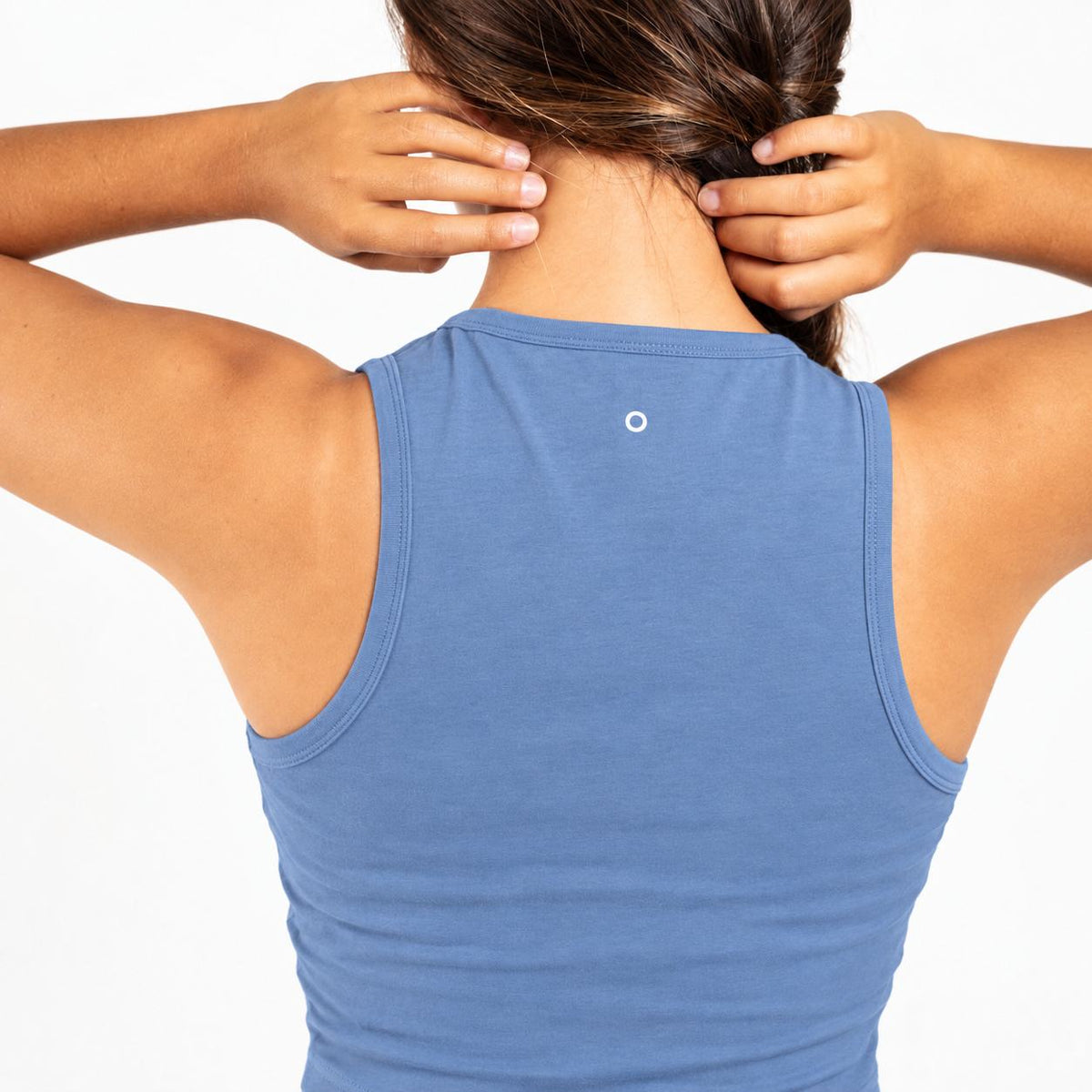 Back view of a woman wearing a heathered blue Organic Cotton Tank Top with built in bra , adjusting her hair with both hands against a plain white background.