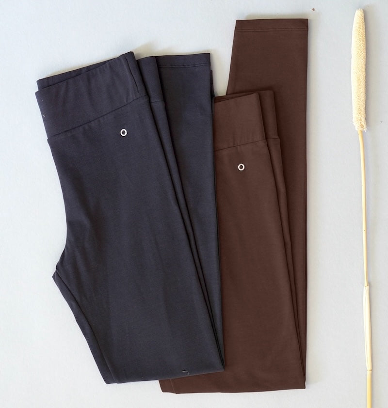 Two pairs of high wasit leggings made of organic cotton , one black and one brown, on a white background.